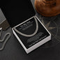 Black message card necklace box for son on a compass-print surface with silver dog tag chain and wood decor