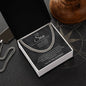 Charcoal message card necklace box for son on compass-print surface with silver dog tag chain and wood decor