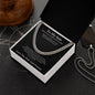 Open gift box with To My Son Cuban link chain and black card on a dark compass-print surface beside a dog tag