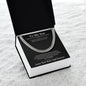 Angled view of open black gift box holding a silver Cuban link chain and To My Son card on white fur