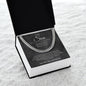 Angled view of open gift box holding a silver Cuban link chain and charcoal To My Son card on white fur
