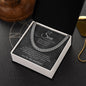 Silver Cuban link chain on charcoal script card in gift box on dark surface beside a gold dog tag chain