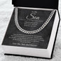 Close-up of a silver Cuban link chain draped over the charcoal To My Son script card in a white box on white fur