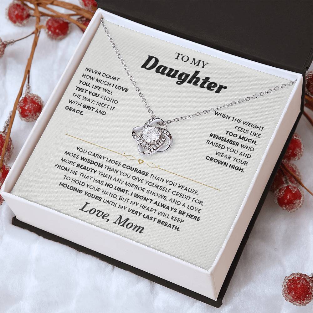 Tilted white gift box holding the white To My Daughter card from Mom and Love Knot necklace among red berries