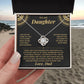 Hand holding the black and gold To My Daughter card from Dad and Love Knot necklace gift box on a beach