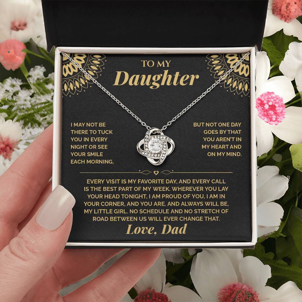 Hand holding the black and gold To My Daughter card from Dad gift box among pink and white flowers