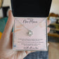 Hand holding open gift box with white gold Love Knot necklace and new mom message card