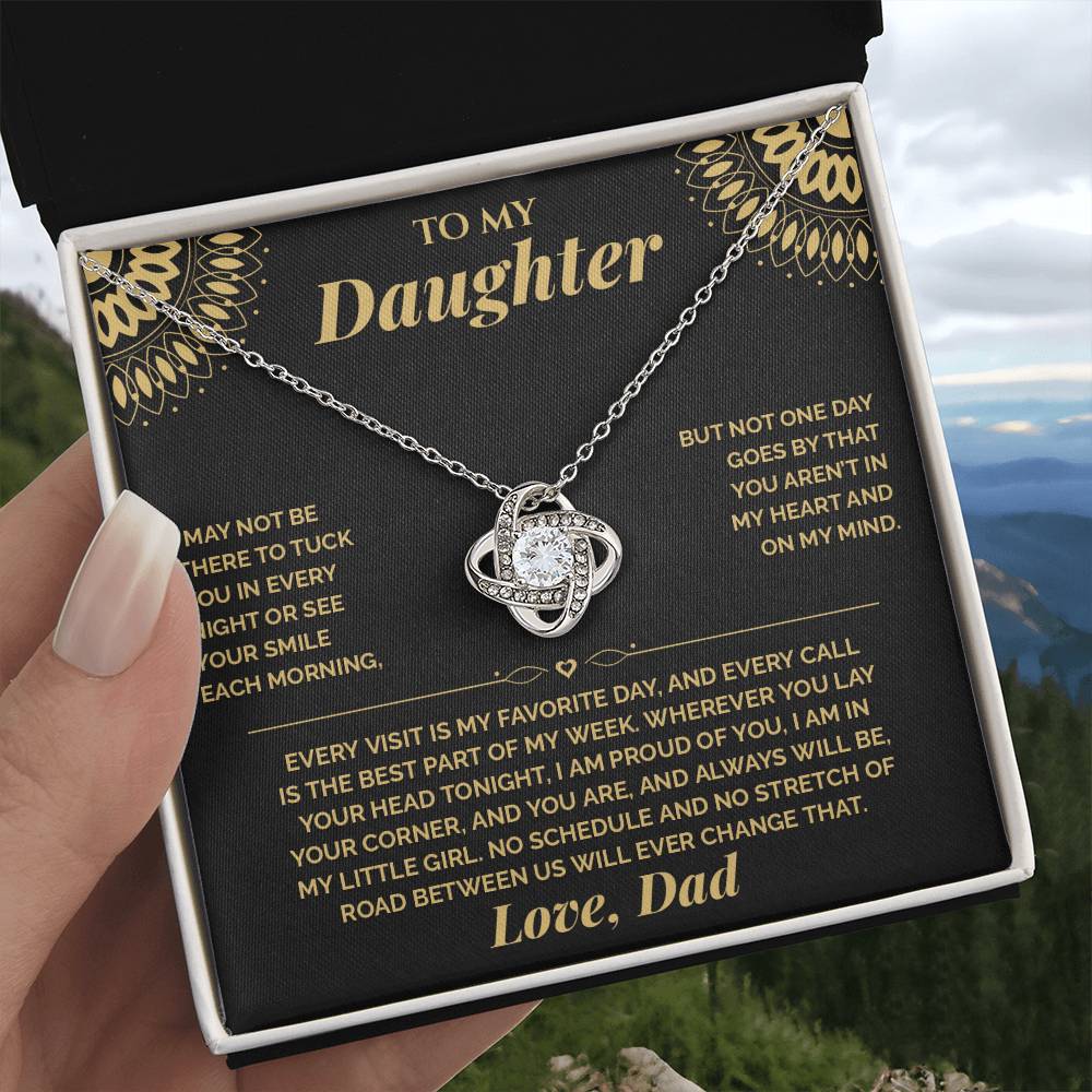 Hand holding the black and gold To My Daughter card from Dad gift box in front of a mountain view