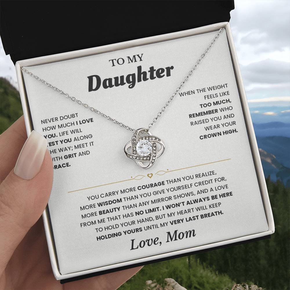 Hand holding the white To My Daughter card from Mom gift box in front of a mountain view
