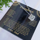 Black and gold To My Daughter card from Dad with the Love Knot necklace laid flat beside green leaves