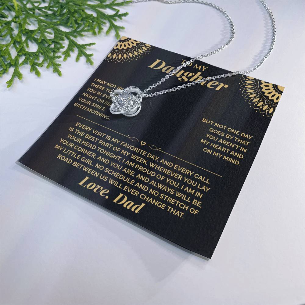 Black and gold To My Daughter card from Dad with the Love Knot necklace beside a pine sprig