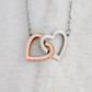 Close-up of the silver-tone and rose gold-tone Interlocking Hearts pendant on white fur