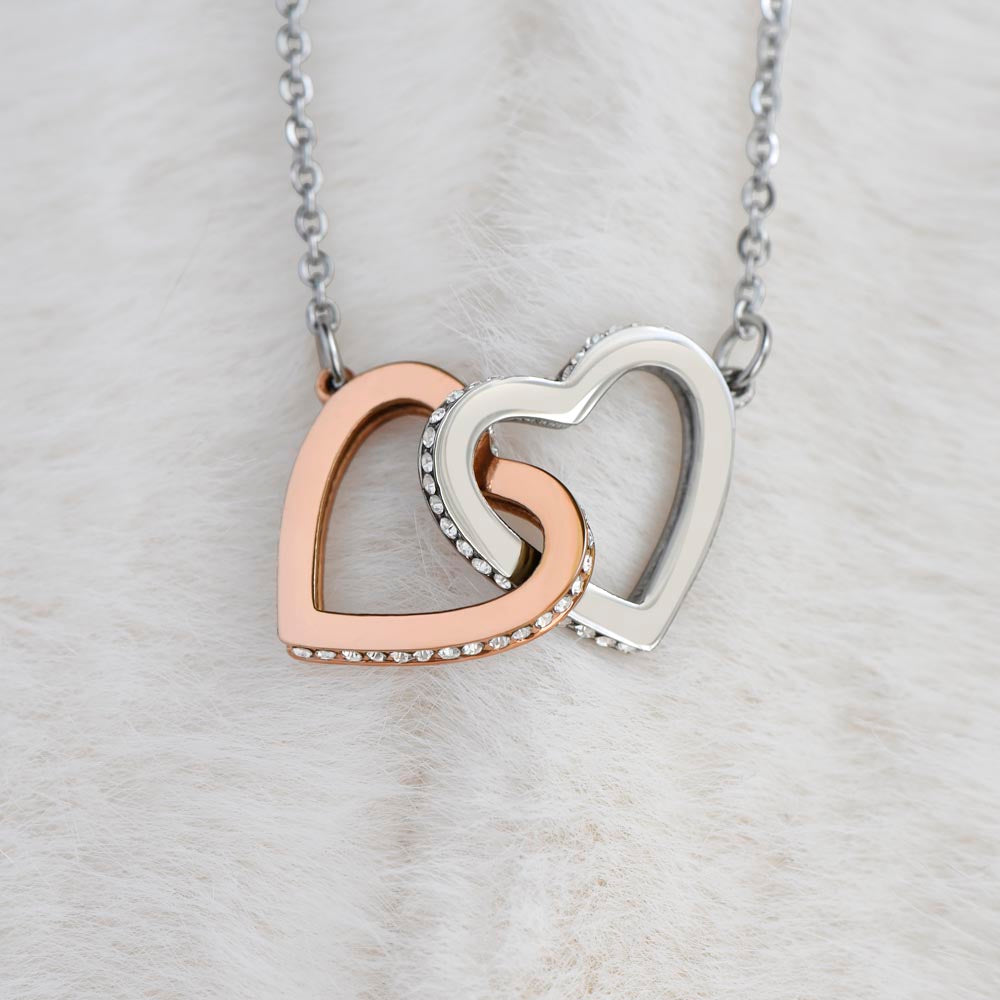 Close-up of the silver-tone and rose gold-tone Interlocking Hearts pendant on white fur