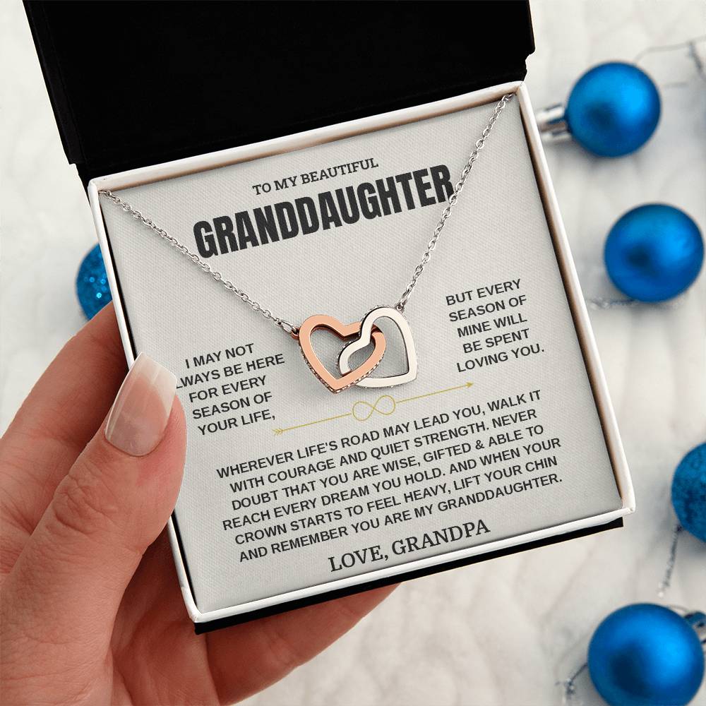 Hand holding the cream Granddaughter card from Grandpa in its gift box beside blue Christmas ornaments