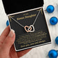 Hand holding the black and gold To My Bonus Daughter card gift box beside blue Christmas ornaments