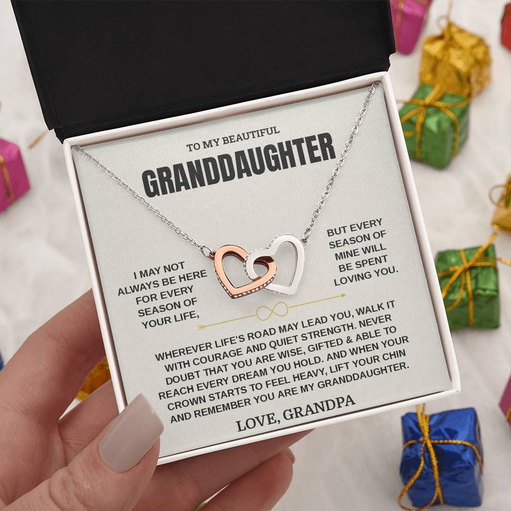 Hand holding the Love, Grandpa card and linked hearts necklace box among wrapped Christmas gifts