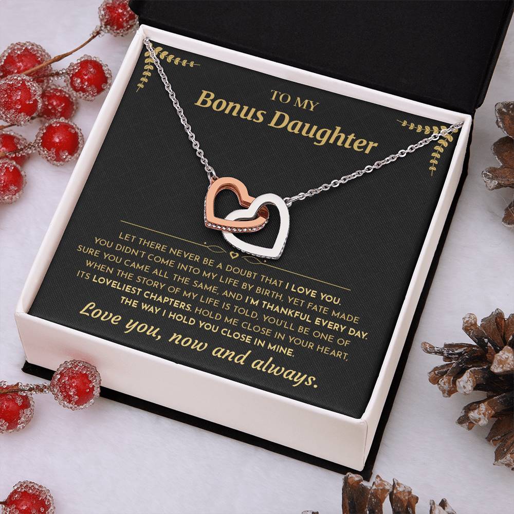Black and gold To My Bonus Daughter card with the Interlocking Hearts necklace in a white gift box with red berries and pinecones