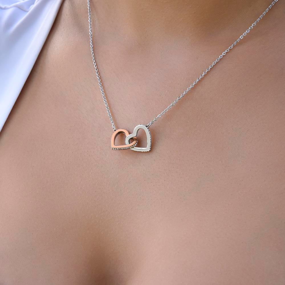 Interlocking Hearts necklace worn with a white top, close-up