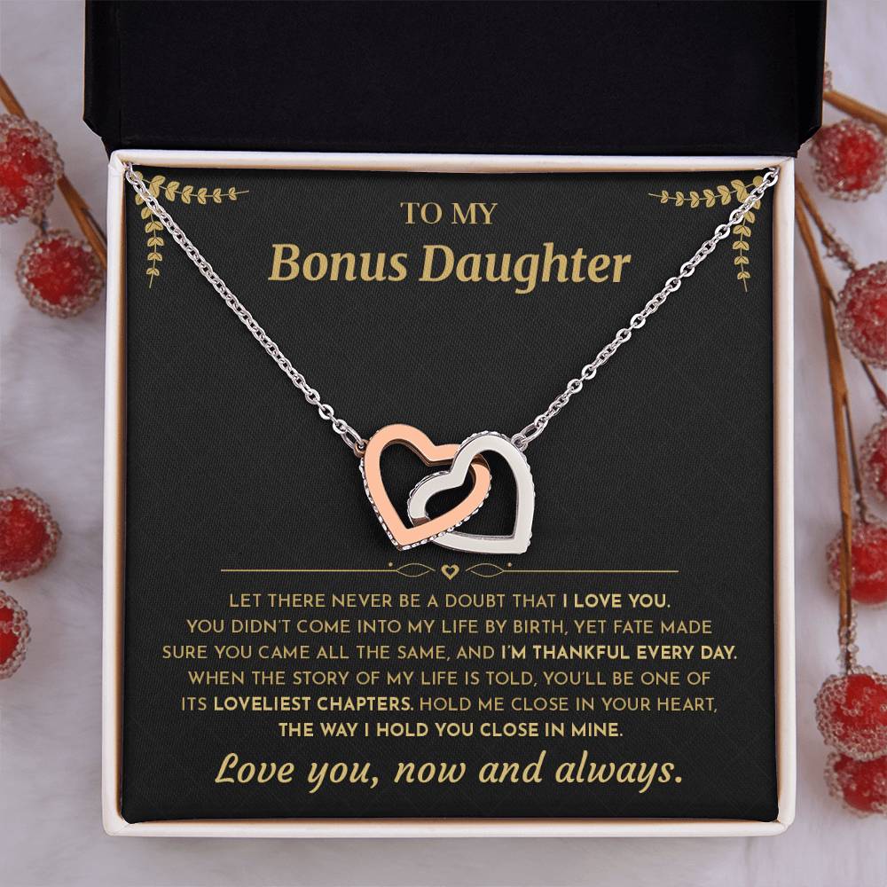 Black and gold To My Bonus Daughter card with the Interlocking Hearts necklace in a gift box beside red berries