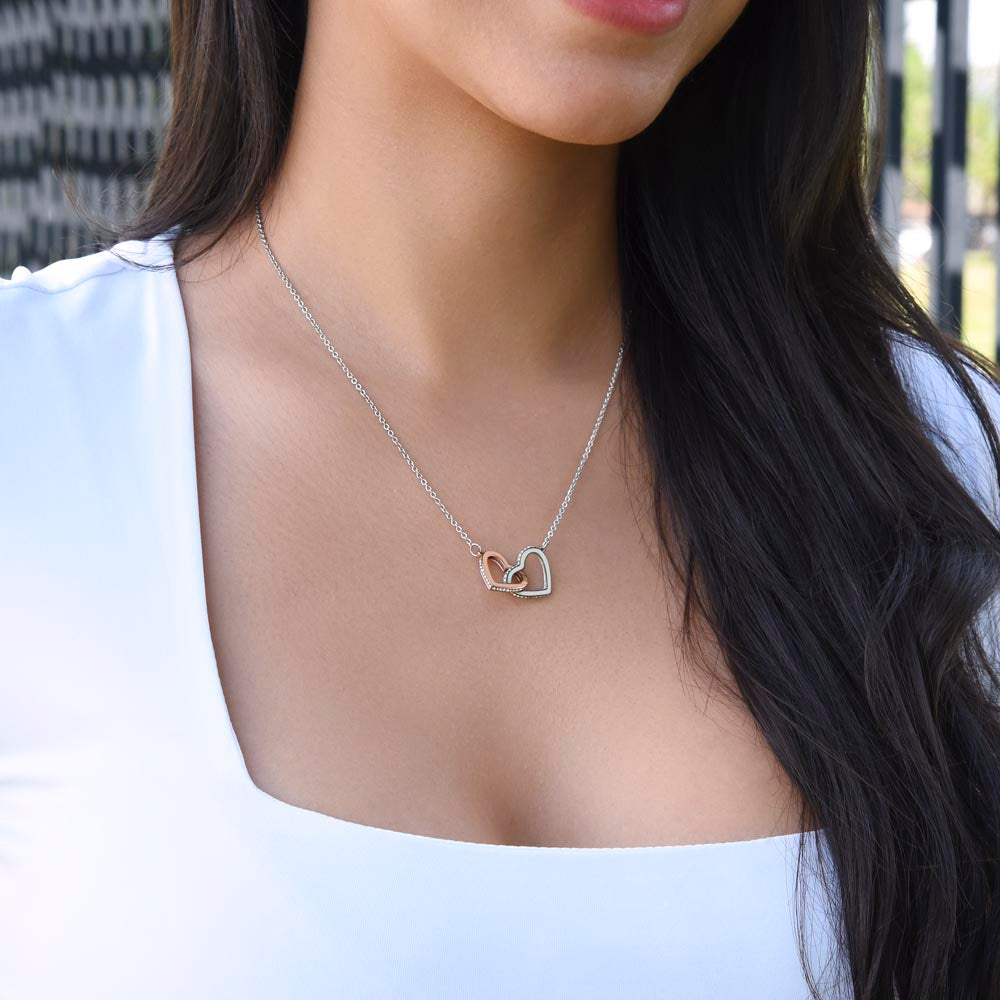 Woman in a white top wearing the Interlocking Hearts necklace