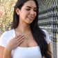 Smiling woman touching the Interlocking Hearts necklace outdoors