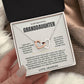 Hand holding an open black gift box with the cream Granddaughter card from Grandpa beside a knit blanket