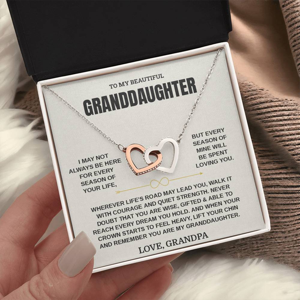 Hand holding an open black gift box with the cream Granddaughter card from Grandpa beside a knit blanket