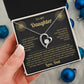 Hand holding the black and gold To My Daughter card from Dad gift box by blue Christmas ornaments on white fur