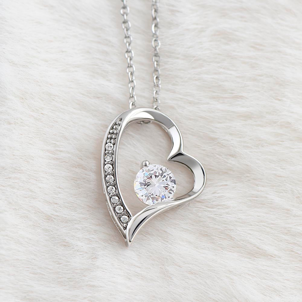 Close-up of the Forever Love heart pendant with round cubic zirconia on white fur (Love, Dad black and gold card set)