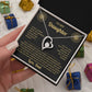 Hand holding the black and gold To My Daughter card from Dad and heart necklace box among wrapped Christmas gifts