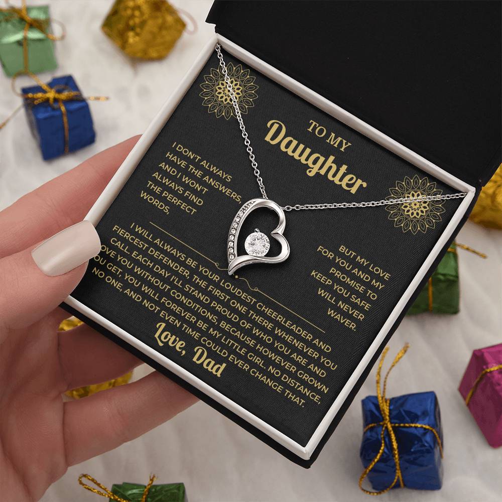 Hand holding the black and gold To My Daughter card from Dad and heart necklace box among wrapped Christmas gifts