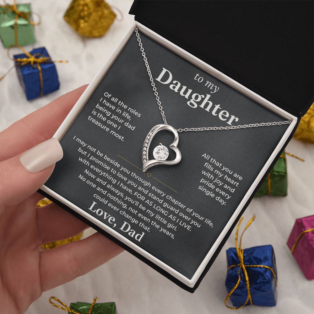 Hand holding the charcoal To My Daughter card from Dad and heart necklace box among wrapped Christmas gifts
