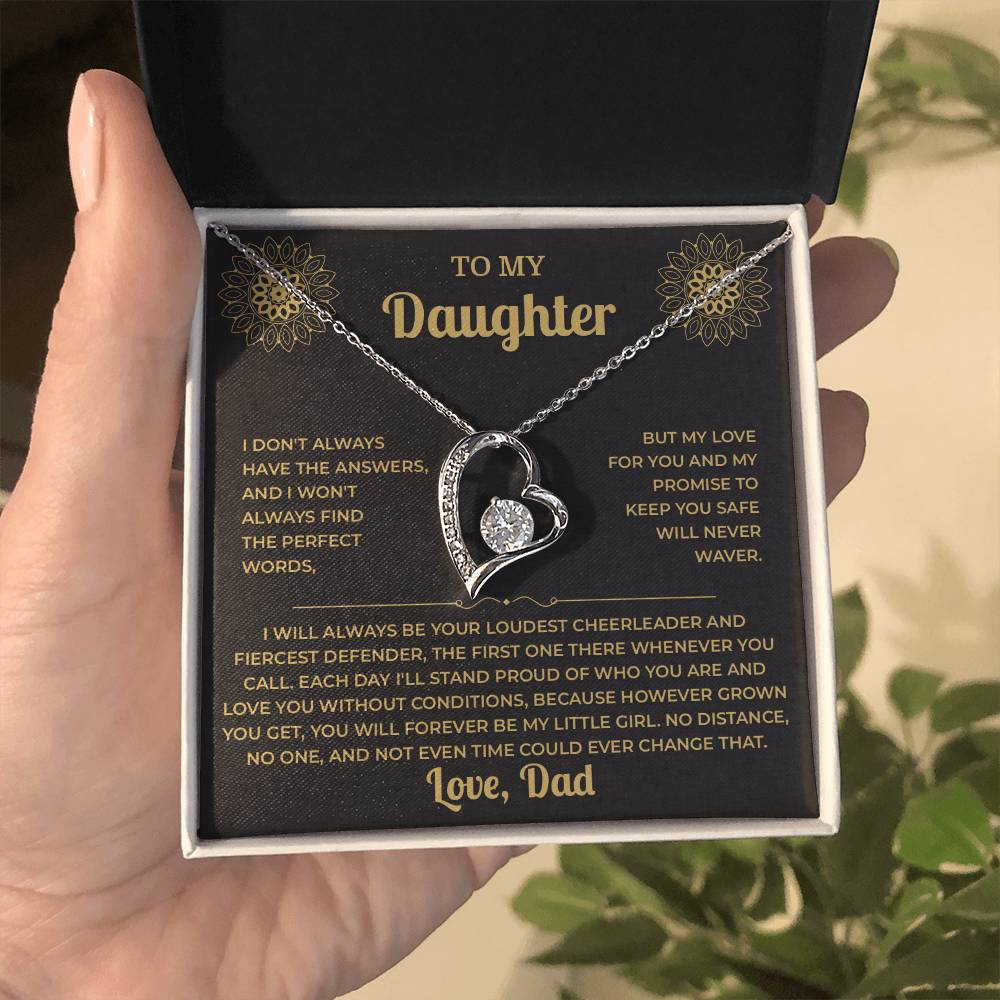 Hand holding an open black gift box with the black and gold To My Daughter card from Dad and heart pendant