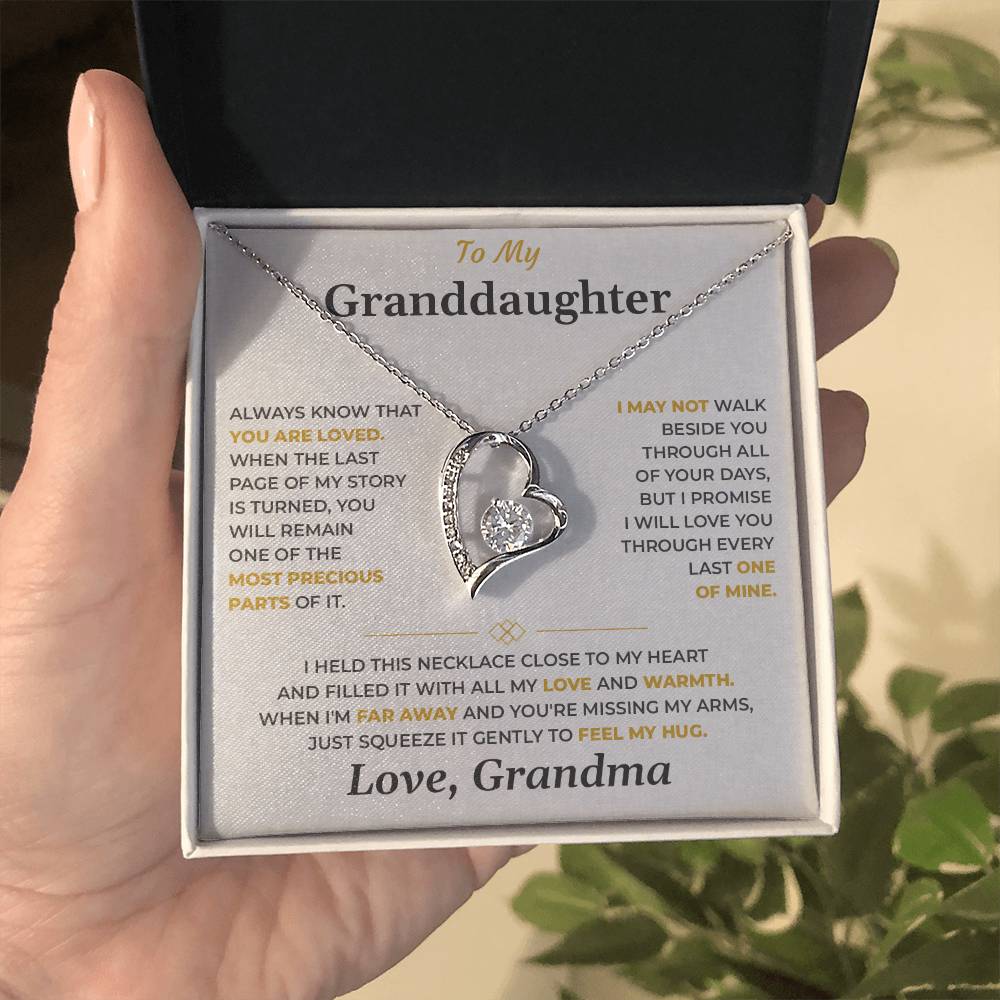 Hand holding an open black gift box with the soft gray To My Granddaughter card from Grandma and heart pendant