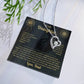 Black and gold To My Daughter card from Dad with heart necklace laid flat beside a pine sprig