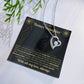 Black and gold To My Bonus Daughter card with heart necklace laid flat beside a pine sprig