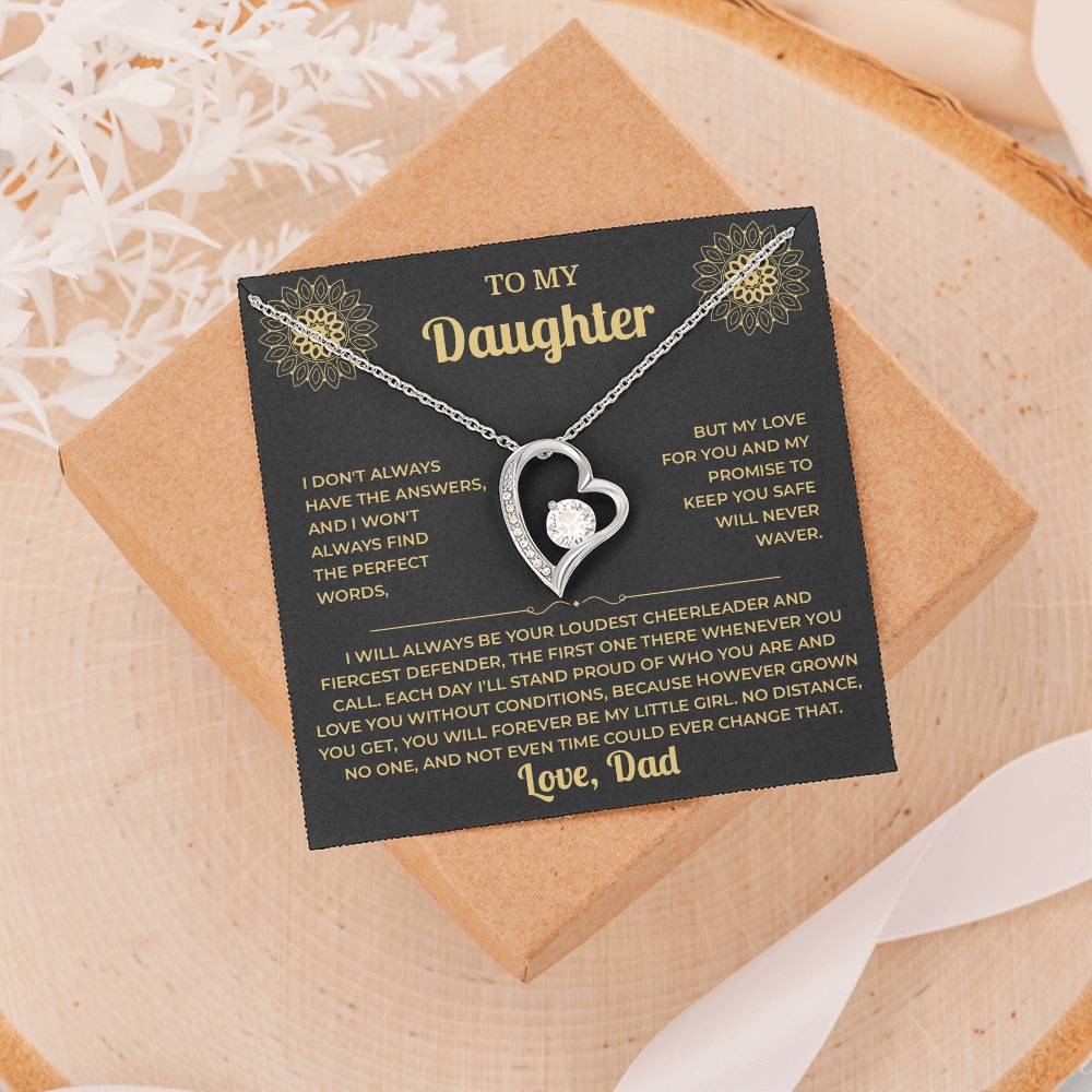 Black and gold To My Daughter card from Dad and heart necklace on a gift box resting on a wood slice with dried flowers