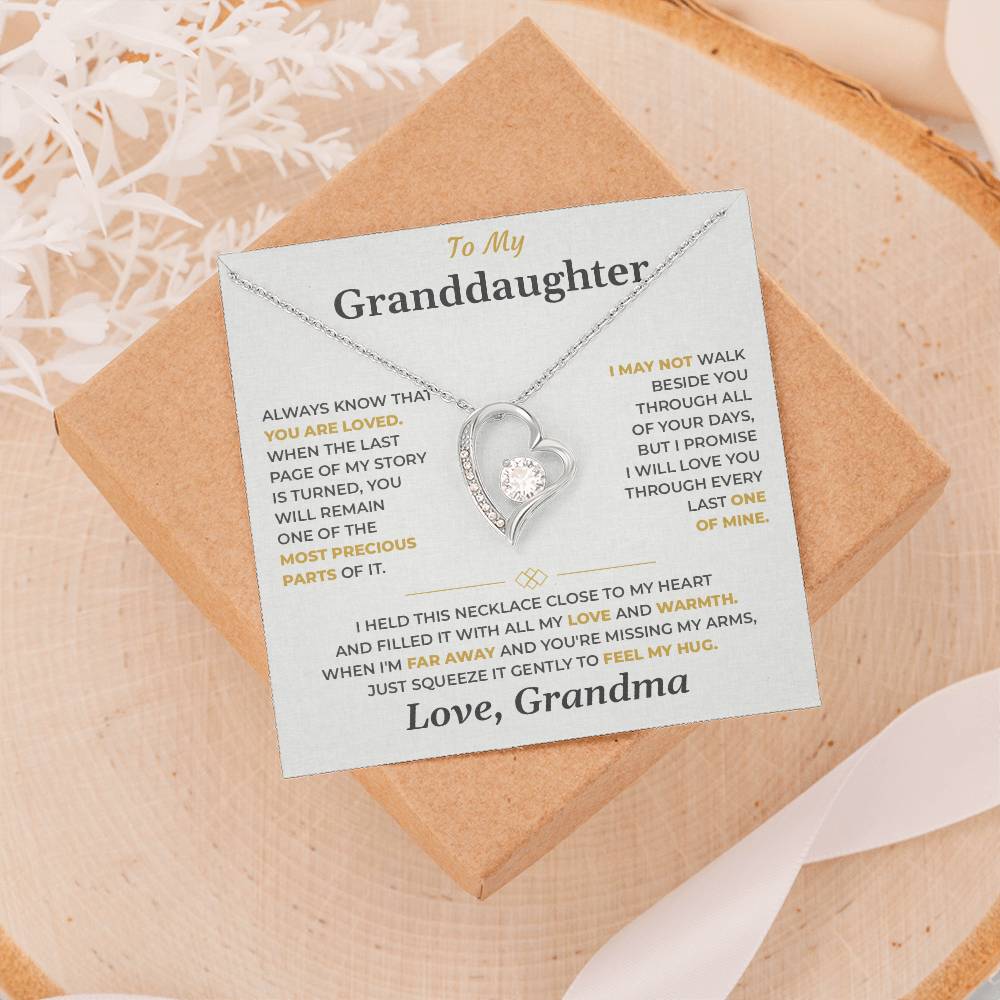 Soft gray To My Granddaughter card from Grandma and heart necklace on a gift box resting on a wood slice with dried flowers