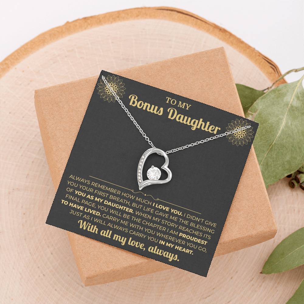Black and gold To My Bonus Daughter card with Forever Love necklace on a wood slice beside greenery