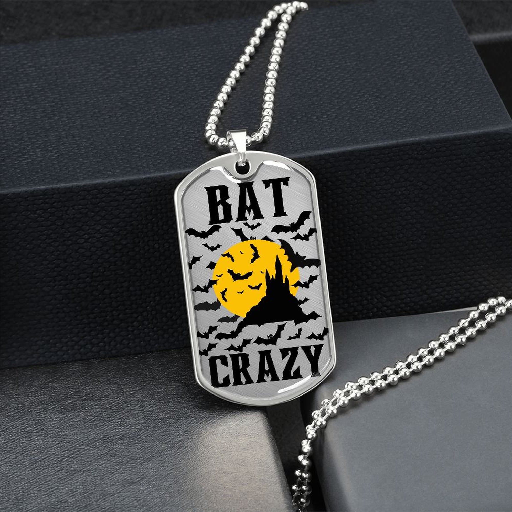 Silver Bat Crazy bat and moon dog tag hanging over a black gift box