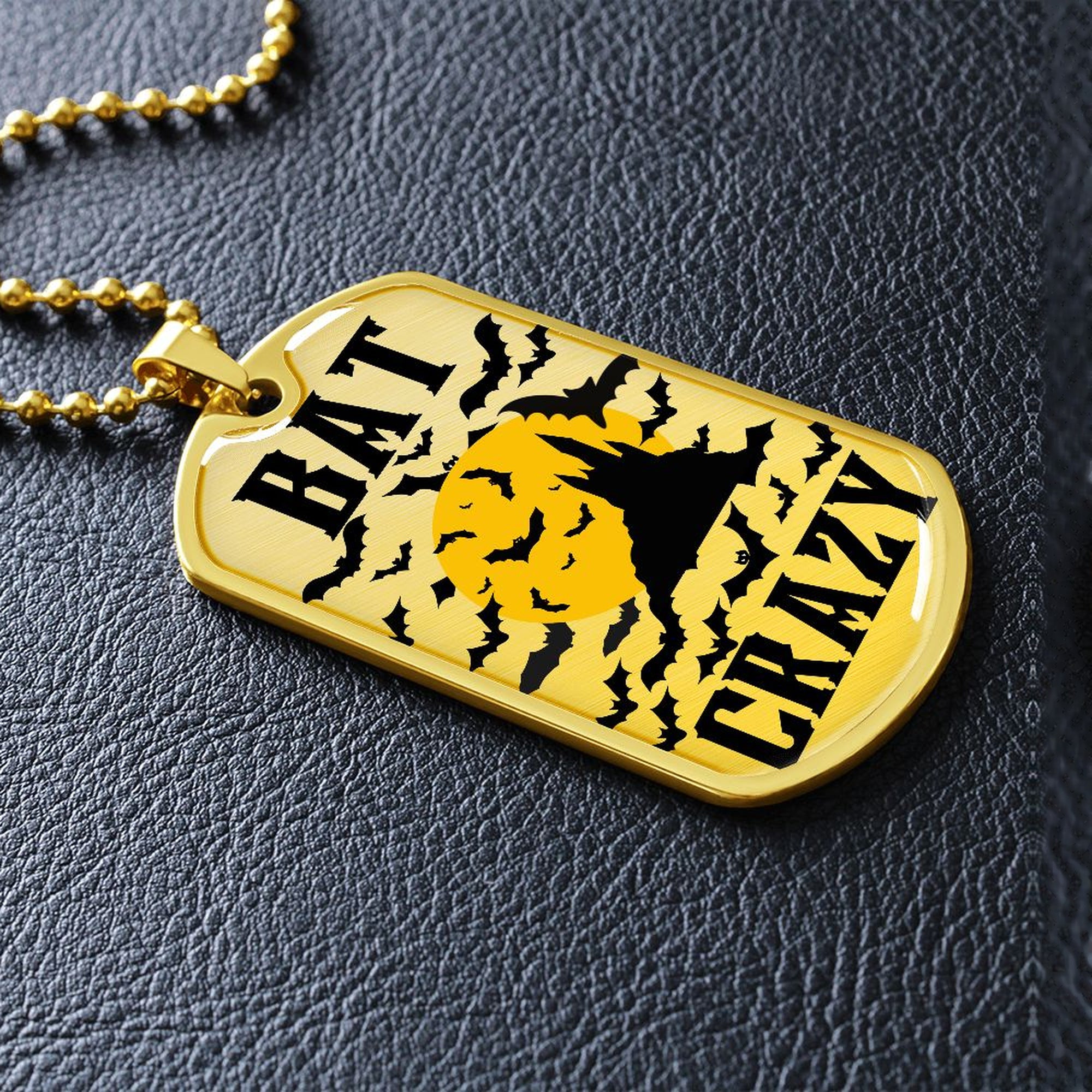 Gold-finish Bat Crazy bat and moon dog tag lying on black leather