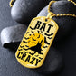 Gold-finish Bat Crazy bat and moon dog tag necklace propped on dark river rocks