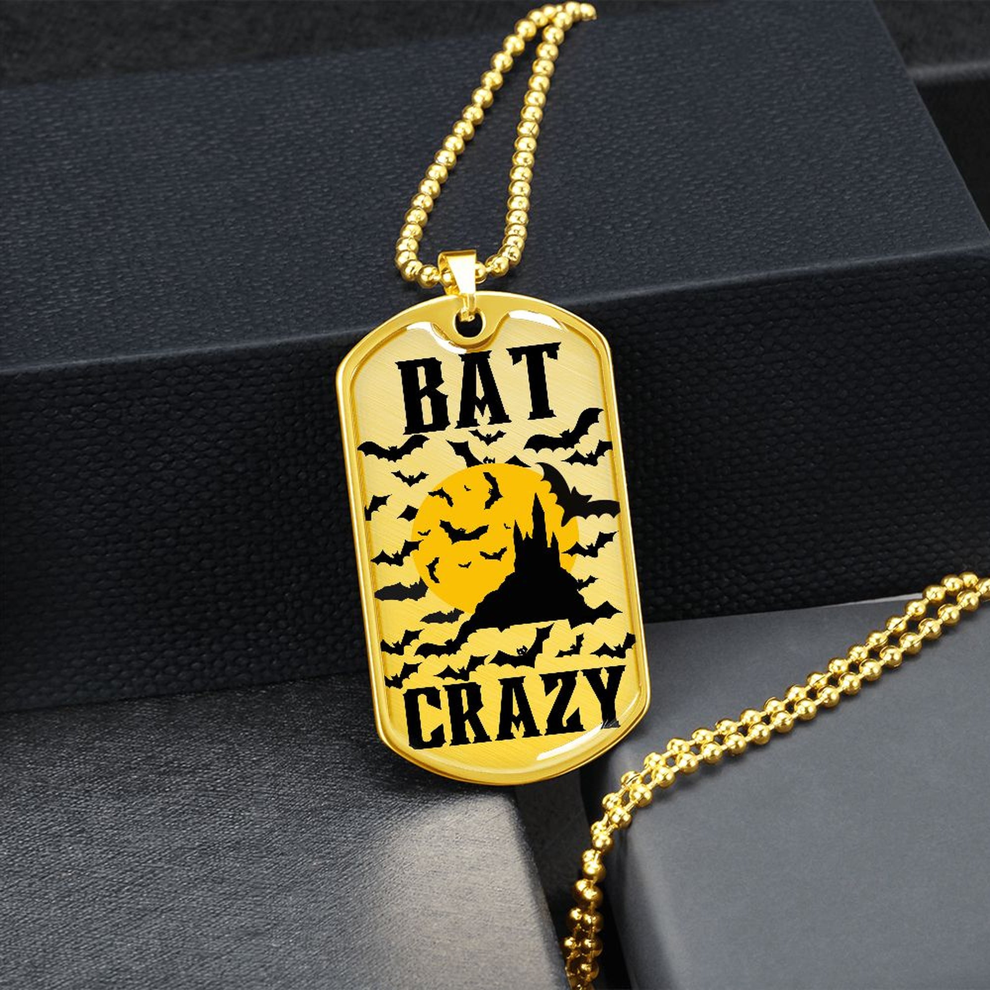 Gold-finish Bat Crazy bat and moon dog tag hanging over a black gift box