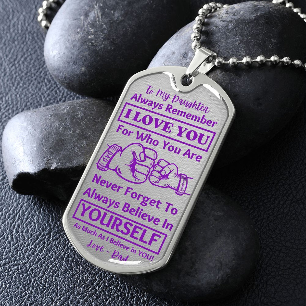 Silver I Love You Daughter dog tag propped on dark river rocks