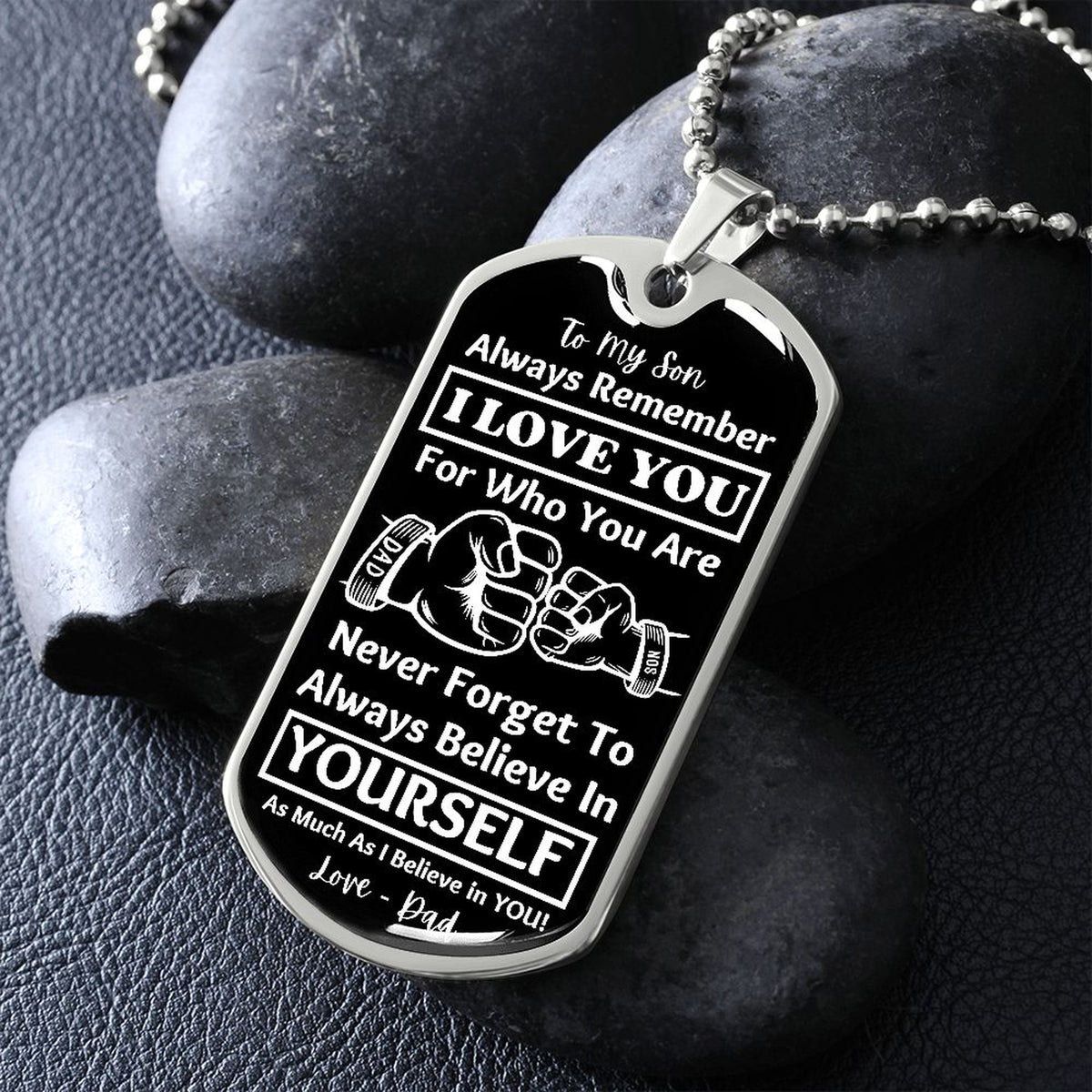 Silver Believe in Yourself son dog tag propped on dark river rocks