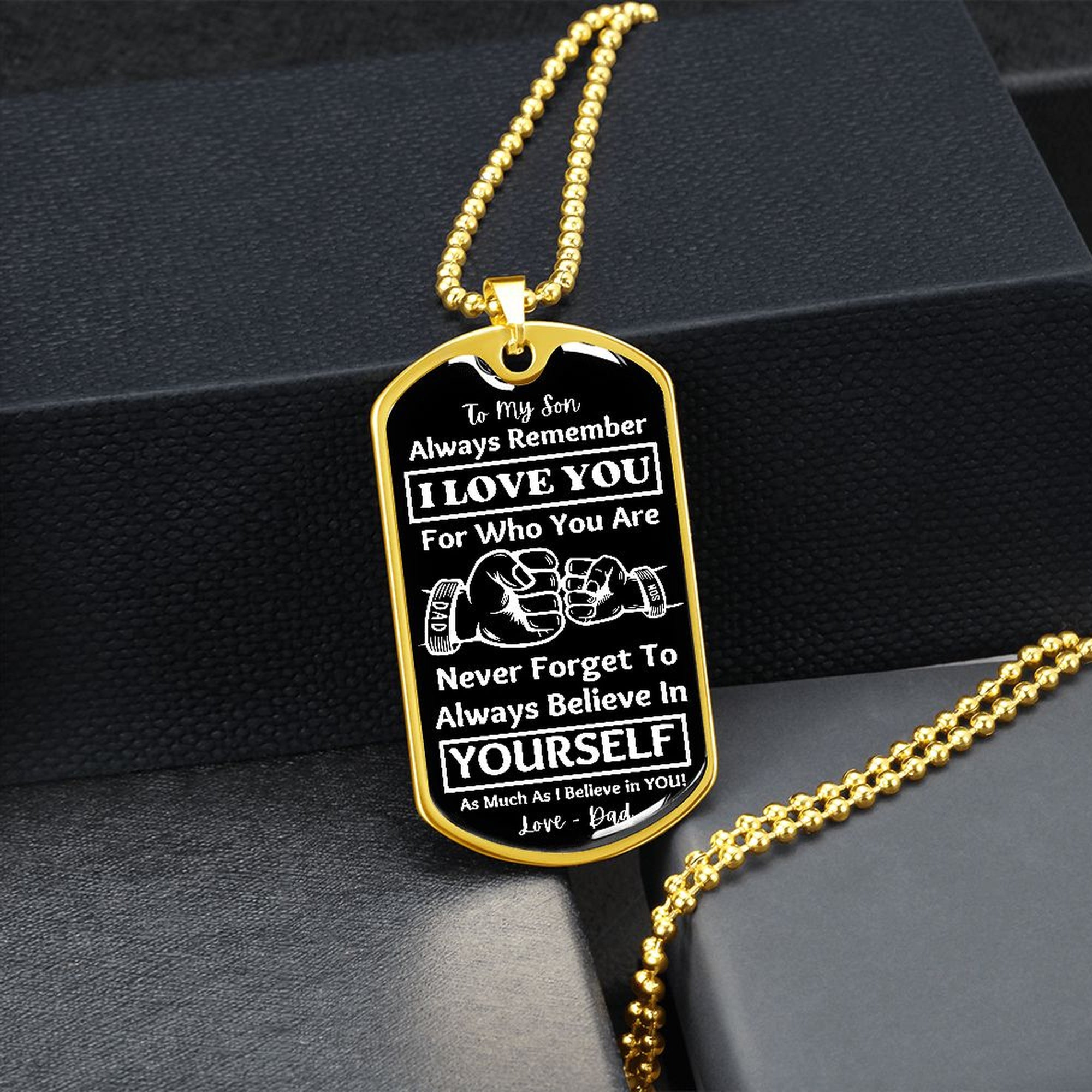 Gold-finish Believe in Yourself son dog tag hanging over a black gift box