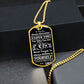 Gold-finish Believe in Yourself son dog tag hanging over a black gift box