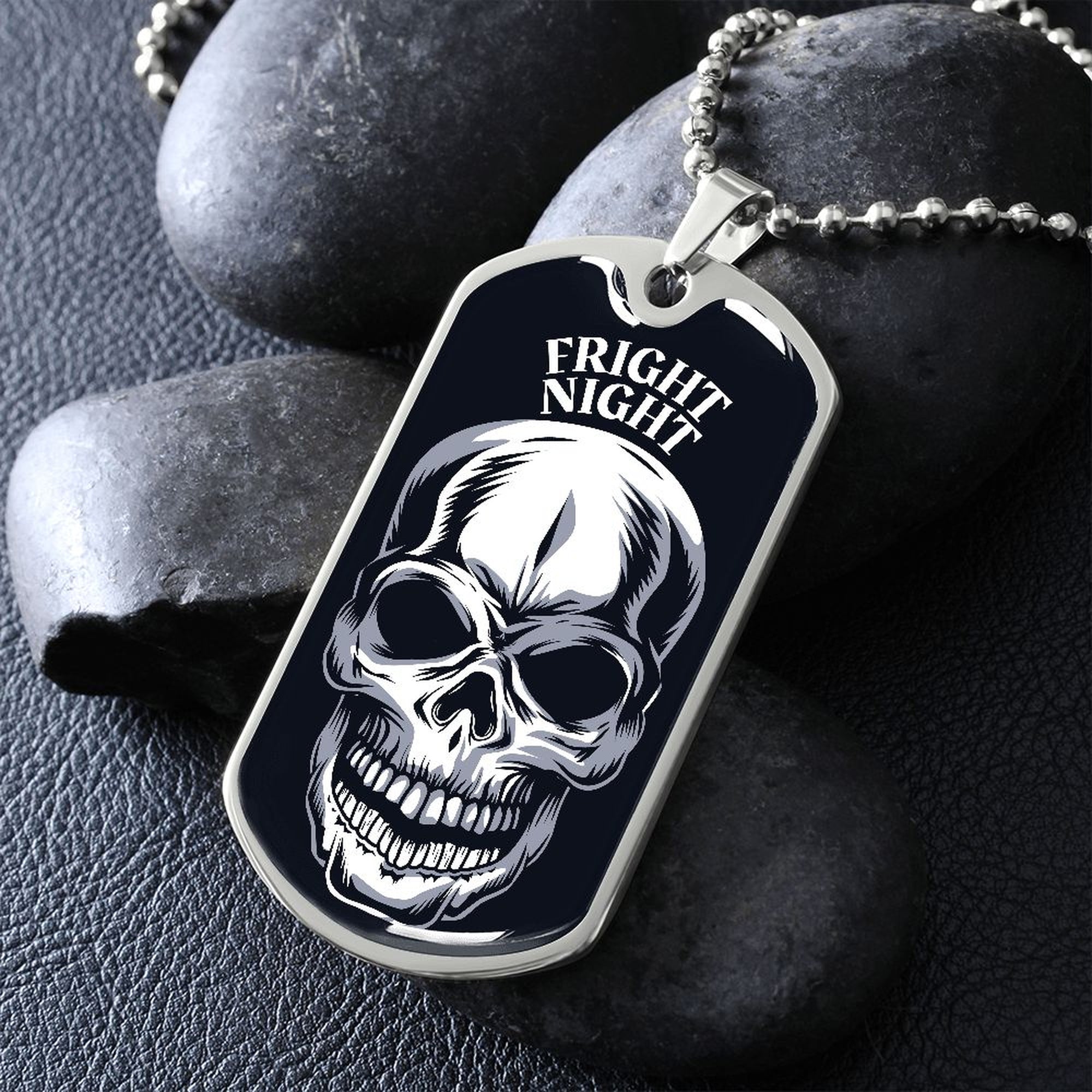 Silver Fright Night skull dog tag necklace propped on dark river rocks