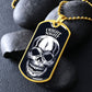 Gold-finish Fright Night skull dog tag necklace propped on dark river rocks