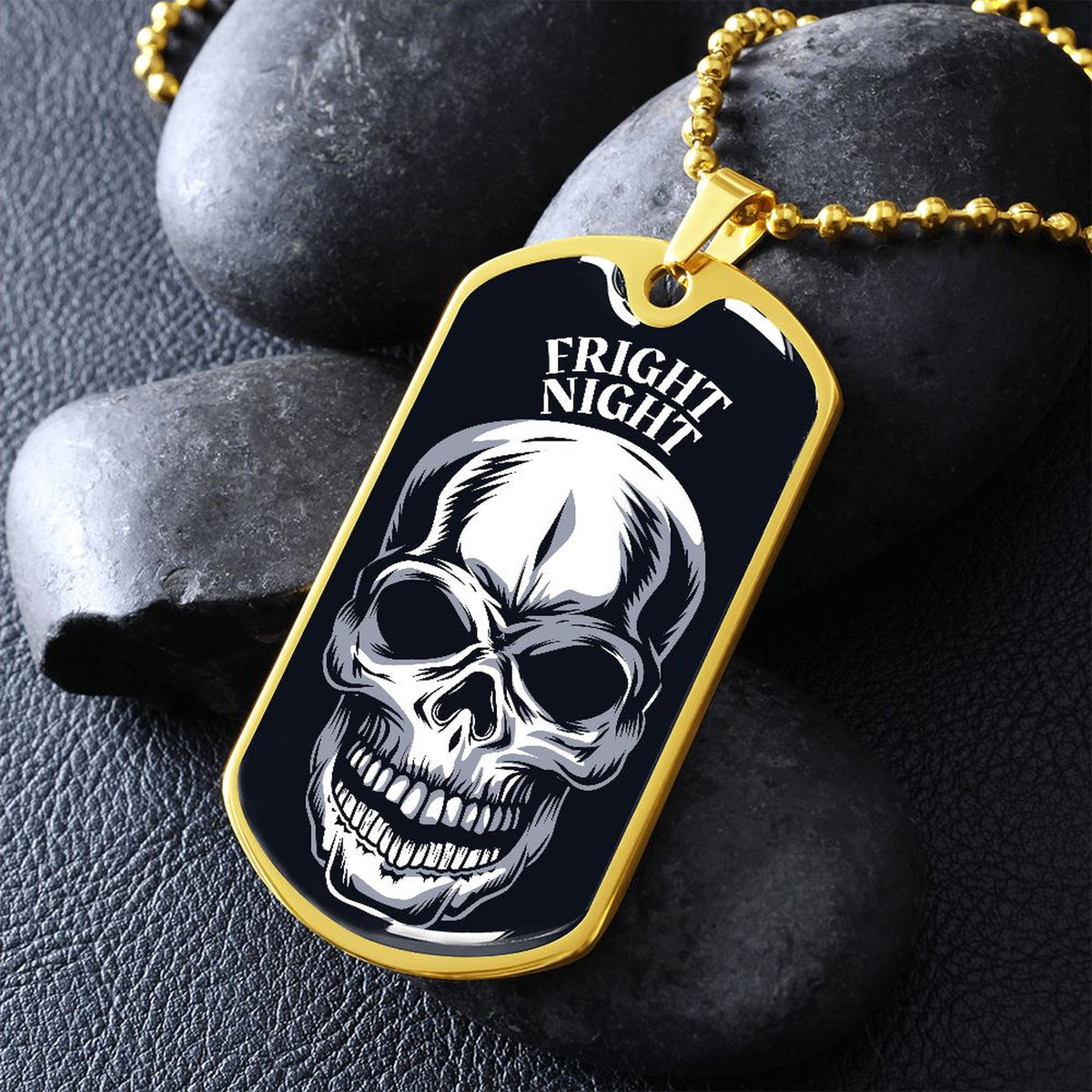 Gold-finish Fright Night skull dog tag necklace propped on dark river rocks